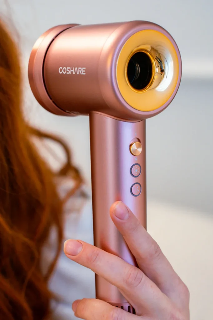 Suszarka do włosów COSHARE SuperFlow1 PRO Rose Gold w dłoni podczas suszenia rudych włosów